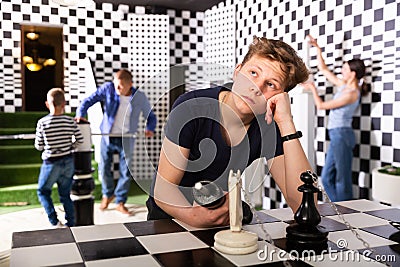 Teenager solving conundrum in quest room stylized under chessboard Stock Photo