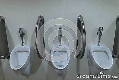 Three ceramic urinals inside the men`s public toilet Stock Photo