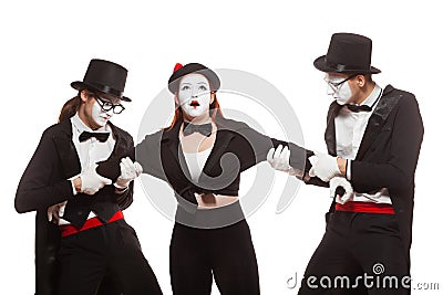 Portrait of three mime artists performing, isolated on white background. Two men pull the girl to sides, can not divide Stock Photo