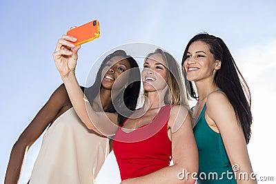 Portrait of three women taking selfies with a smartphone. Stock Photo