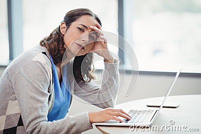 Portrait tired executive using laptop at desk Stock Photo