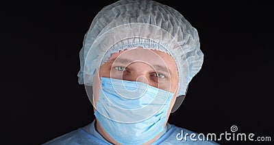 Portrait. Tired eyes of the surgeon look at the camera on a black isolated background. A doctor in a surgical uniform is Stock Photo