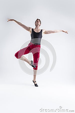 Portrait of Tranquil Contemporary Ballet of Flexible Athletic Man Posing in Red Tights in Ballanced Dance Pose With Hands In Line Stock Photo