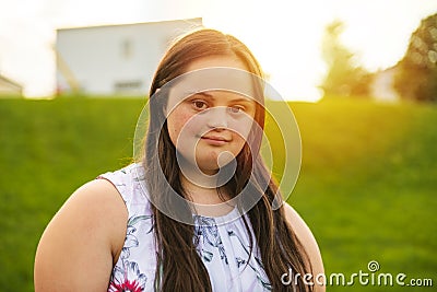 A Portrait of trisomie 21 adult girl outside at sunset Stock Photo