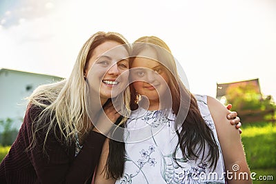 A Portrait of trisomie 21 adult girl smilin outside at sunset with family friend Stock Photo