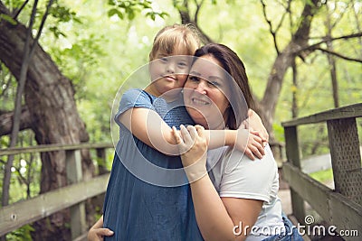 A portrait of trisomie 21 child girl outside with his mother Stock Photo