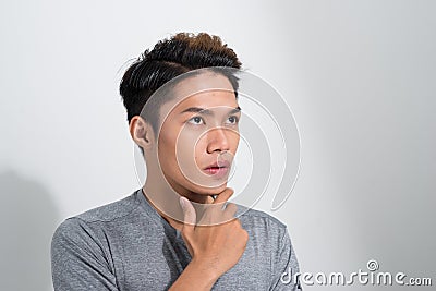 Portrait of troubled young asian guy trying think up plan or idea, standing in thoughtful pose with hand on chin Stock Photo