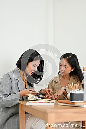 Portrait, Two asian female graphic designers examining a colour swatches palette together Stock Photo