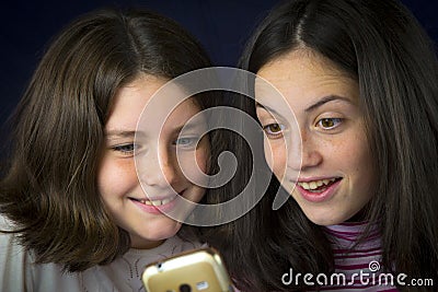 Portrait of two cute sisters looking at cell phone Stock Photo