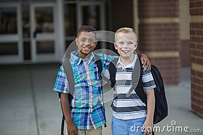 Portrait of Two diverse school kids standing outside their elementary school building Stock Photo