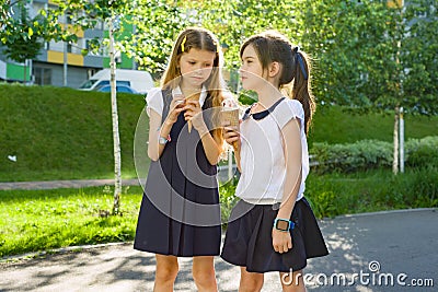 Portrait of two girlfriends schoolgirls 7 years old in school uniform eating ice cream. Stock Photo