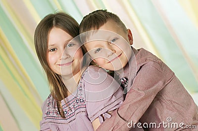 Portrait of the two hugging siblings over stripped green-yellow background Stock Photo