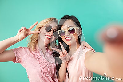 Portrait of two joyful women vin sunglasses isolated on blue Stock Photo
