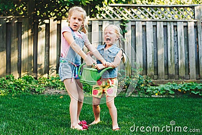 Two little girls sisters having fight on home backyard Stock Photo