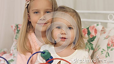 Portrait of two lovely sisters sitting on a bed with a toy Stock Photo