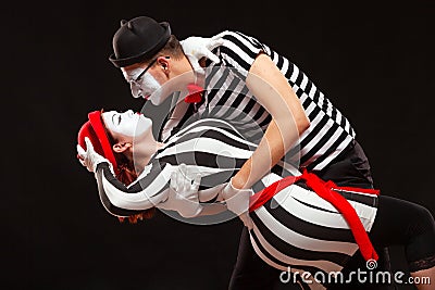 Portrait of two mime artists performing, isolated on black background. Man leaning his woman while dancing. Symbol of Stock Photo