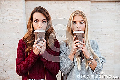 Portrait of a two pretty shocked girls holding coffee cups Stock Photo