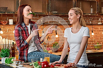 Eat right, Live strong. Young female friends preparing together vegetarian meal in modern kitchen. Cozy interior Stock Photo