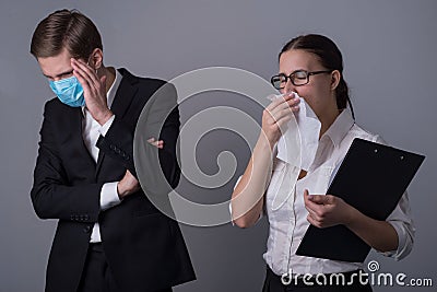 Portrait of two young businessmen in business clothes. The masked guy covers his face with his hand, fearing infection by a sick Stock Photo