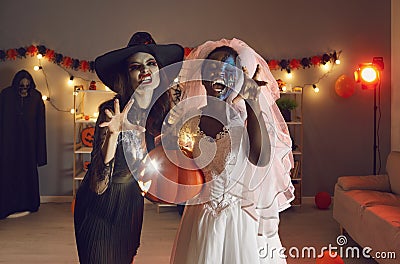 Portrait of two young women dressed in Halloween costumes of Witch and Dead Bride Stock Photo