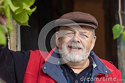 Portrait of Ukrainian bearded smiling senior peasant against old barn entry Stock Photo