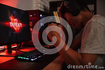 Portrait of unhappy asian teenage gamer boy losing while playing Stock Photo