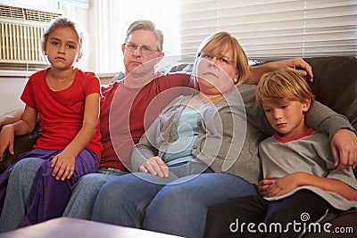 Portrait Of Unhappy Family Sitting On Sofa Together Stock Photo