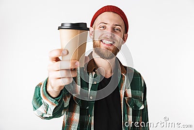 Portrait of unshaved man wearing hat and plaid shirt holding paper cup with coffee, while standing isolated over white background Stock Photo