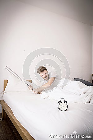 Portrait upset angry with baseball hit young man screaming at alarm clock on bedroom. Stock Photo