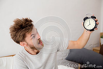 Portrait upset angry young man screaming at alarm clock Stock Photo