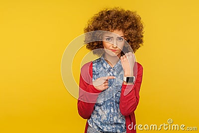 Portrait of upset impatient woman with curly hair showing wrist watch and looking disappointed at camera Stock Photo
