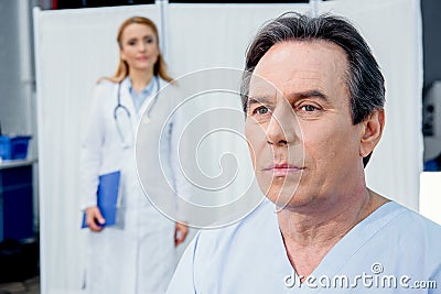 Portrait of upset middle aged patient with doctor behind Stock Photo