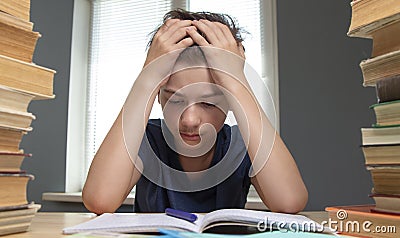 Portrait of upset schoolboy looking at textbook with homework Stock Photo