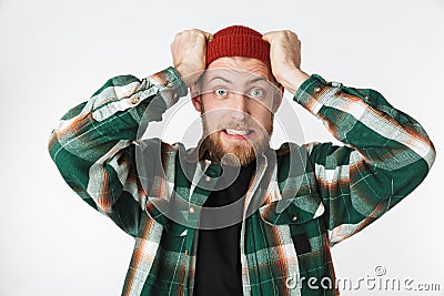 Portrait of uptight man wearing hat and plaid shirt screaming and grabbing head, while standing isolated over white background Stock Photo
