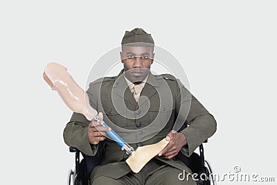 Portrait of US military officer in wheelchair holding prosthesis foot over gray background Stock Photo