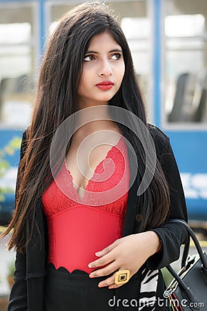 Portrait of very beautiful straight haired young attractive Indian woman wearing red outfit with black jacket posing fashionable Stock Photo