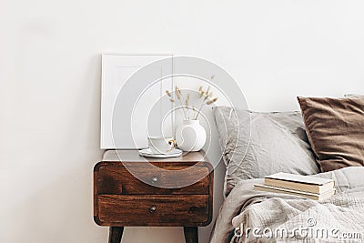 Portrait white frame mockup on retro wooden bedside table. Modern white ceramic vase with dry Lagurus ovatus grass and Stock Photo