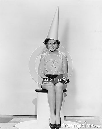 Portrait of woman with April Fool sign wearing dunce cap Stock Photo
