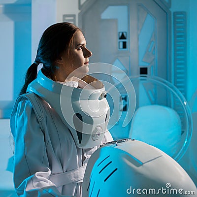 Portrait of a woman astronaut in a space suit, dreamy look up. Futuristic astronaut on Board the spacecraft. Stock Photo