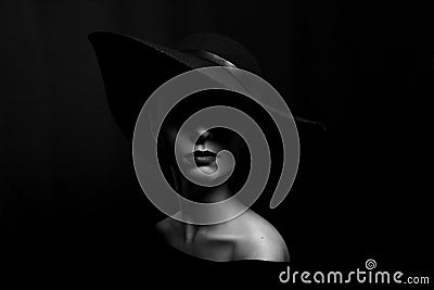 Portrait of a woman in a black hat on a black background black and white photo Stock Photo