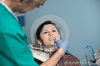 Portrait of woman in dental clinic office. Dentist checking and selecting color of the teeth. Dentistry Stock Photo