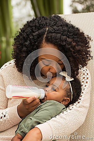 Portrait of woman feeding her daughter with a bottle. Stock Photo