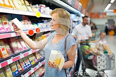 Portrait of woman holding assortment of cheese in grocery shop Stock Photo