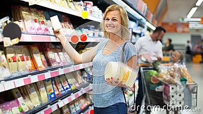 Portrait of woman holding assortment of cheese in grocery shop Stock Photo