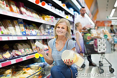 Portrait of woman holding assortment of cheese in grocery shop Stock Photo