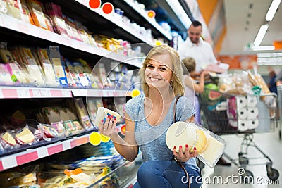 Portrait of woman holding assortment of cheese in grocery shop Stock Photo