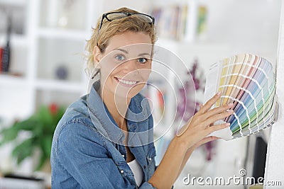 Portrait woman holding colour chart against interior wall Stock Photo