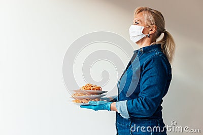 Portrait of woman holding plates of Italian pasta wearing protective surgical mask and latex gloves Stock Photo