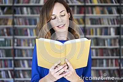 Portrait of woman in a library with opened book hold in hands, long hair. Young college student girl in co-working Stock Photo