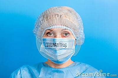 Portrait of woman in medical uniform and mask with word at blue background. Respiratory protection. Coronavirus Stock Photo